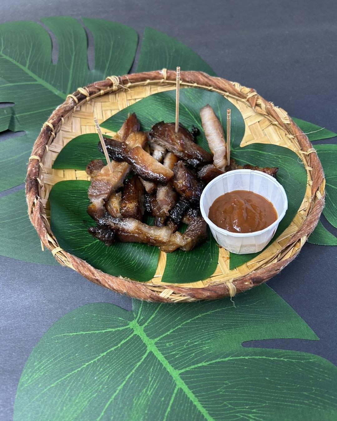 Du boucané servi dans un panier tressé, sur une feuille de monstera